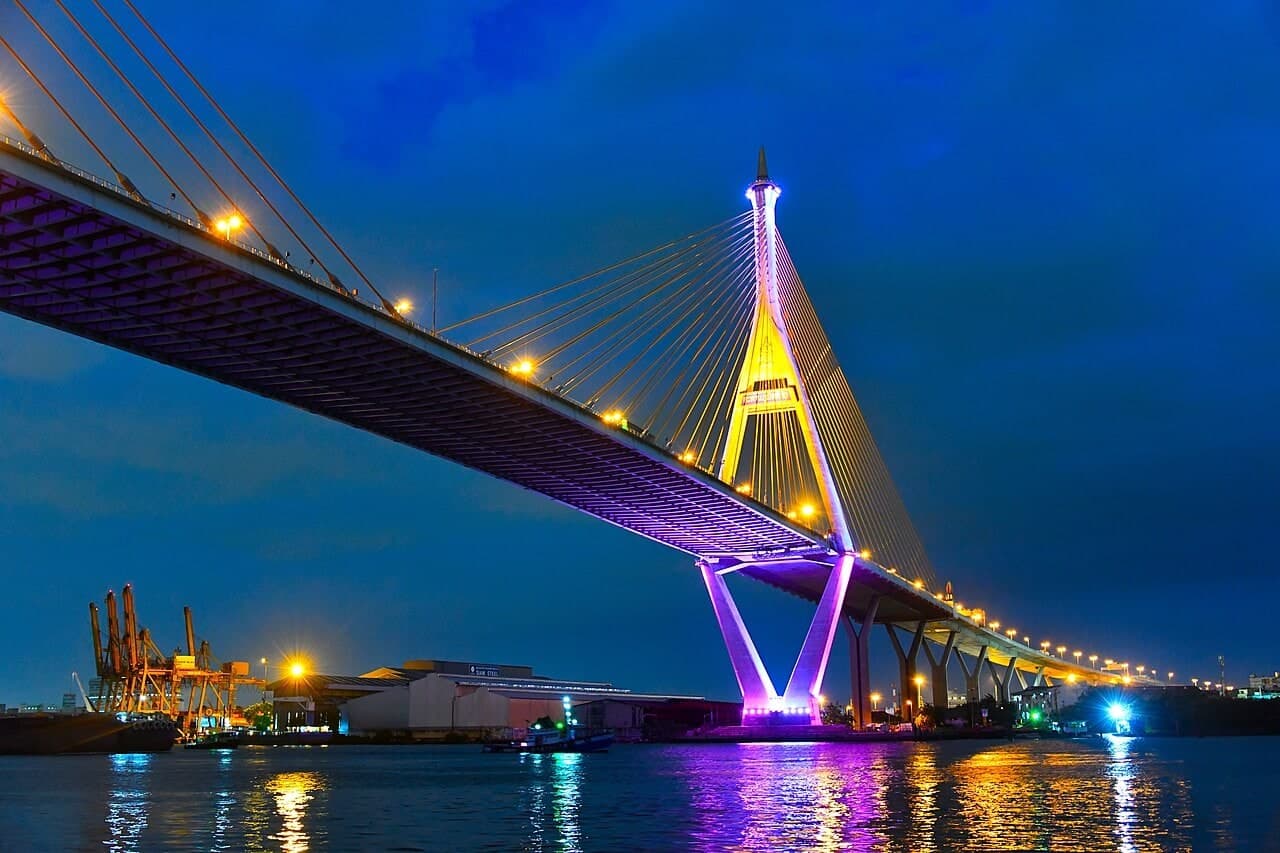 普密蓬大桥群：普密蓬二号桥夜景近景，紫色桥面灯带、金色桥塔和斜拉索占据画面主体。