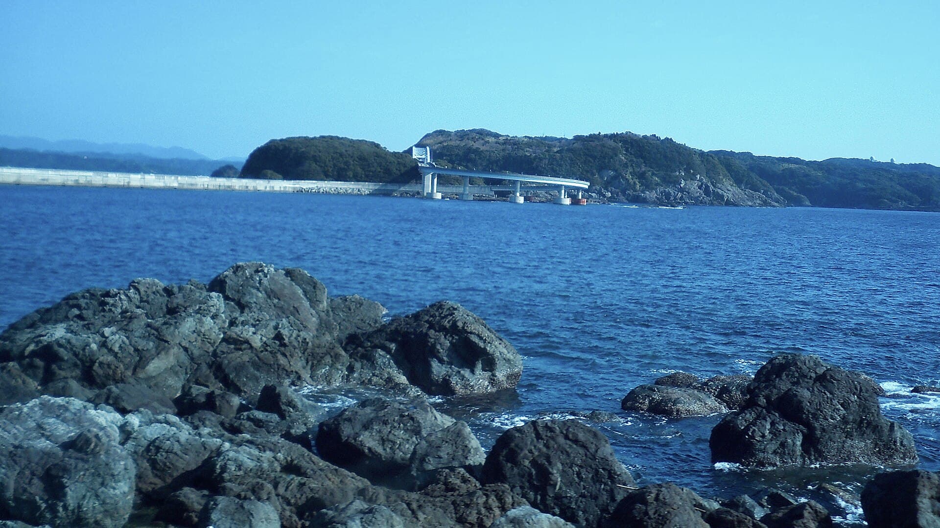 串本大桥：串本大桥：Wikimedia Commons 文件「Kushimoto Bridge View from Shiono Misaki 20100214b.JPG」中的桥梁实景。