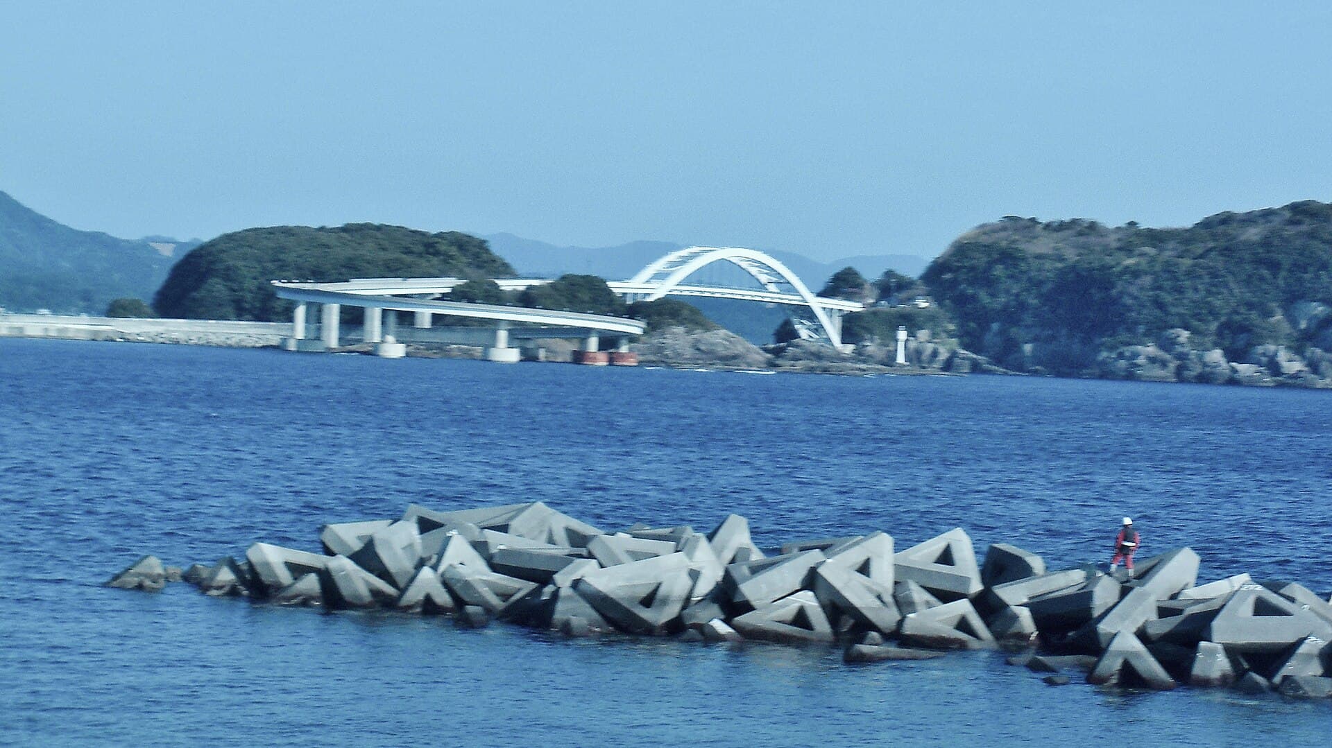 串本大桥：串本大桥：Wikimedia Commons 文件「Kushimoto Bridge View from Shiono Misaki 20100214c.JPG」中的桥梁实景。