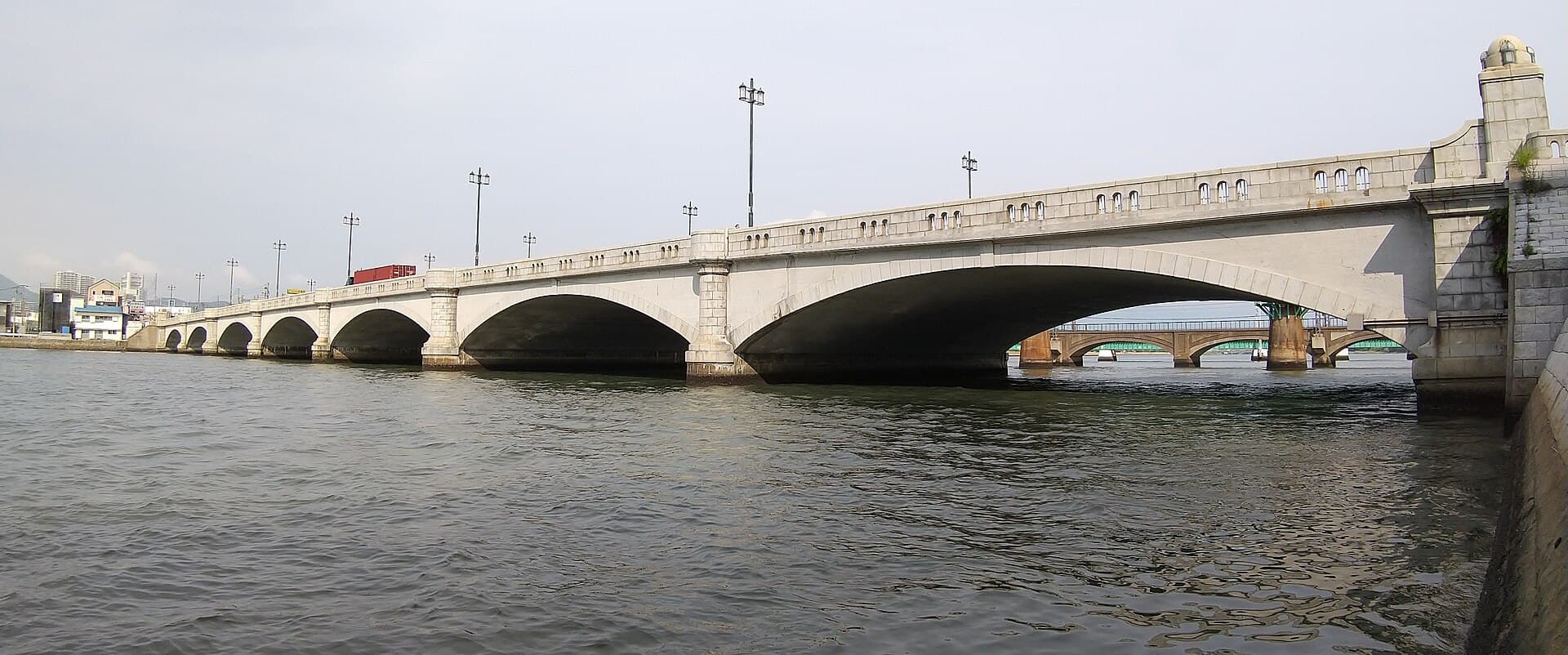名岛桥：名岛桥：Wikimedia Commons 文件「Najima Bridge ENE from the downstream left bank Najima 2-chōme and Hakozaki 7-chōme Higashi-ku Fukuoka 20230623.jpg」中的桥梁实景。