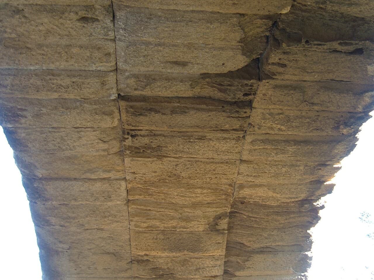 加尔桥：从拱下仰看石拱内弧、券石和相邻桥墩，画面主体是拱底结构。