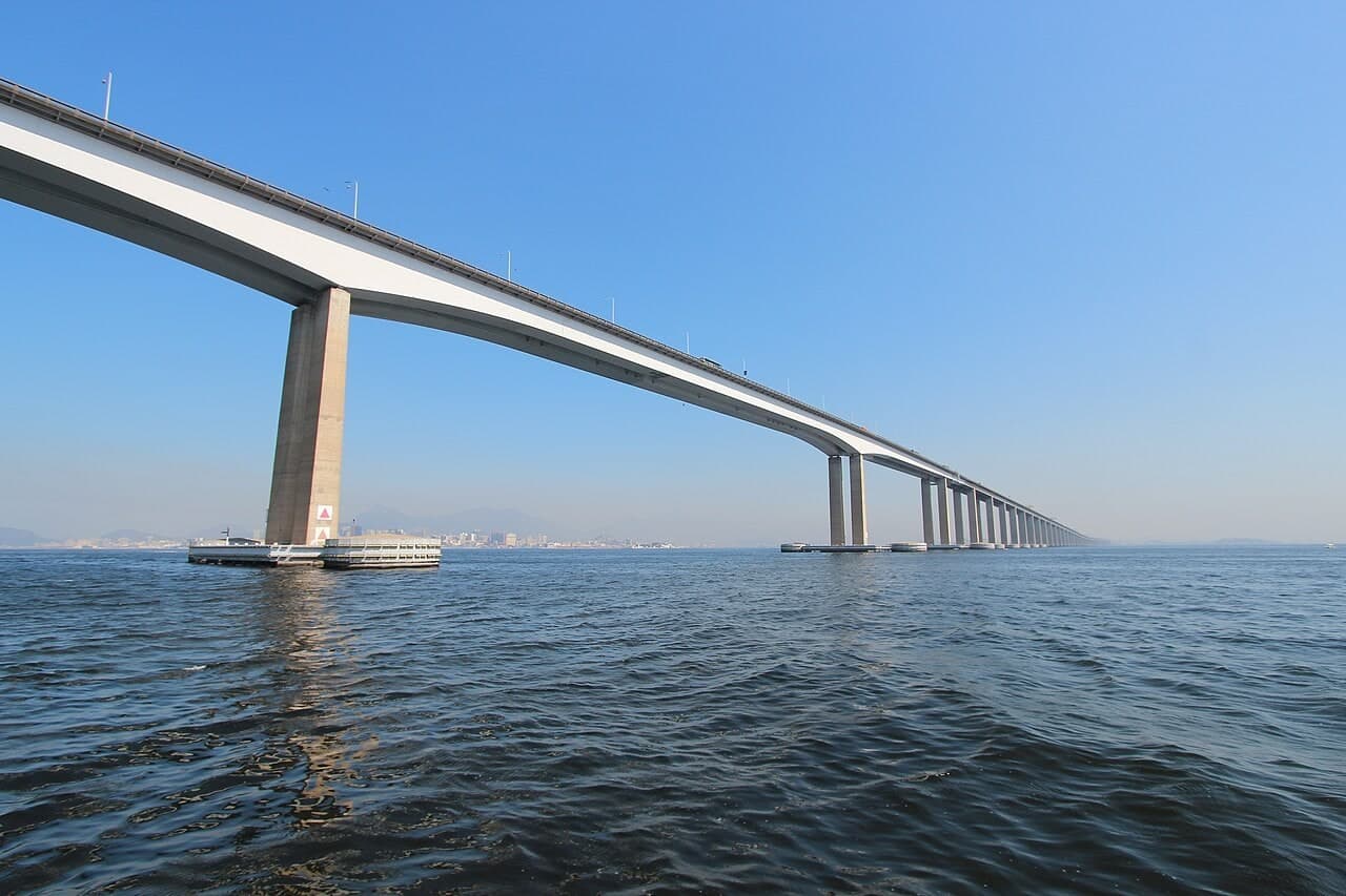 里约—尼泰罗伊大桥：靠近主跨桥下仰拍，强逆光下可见箱梁底面、桥墩和海面。