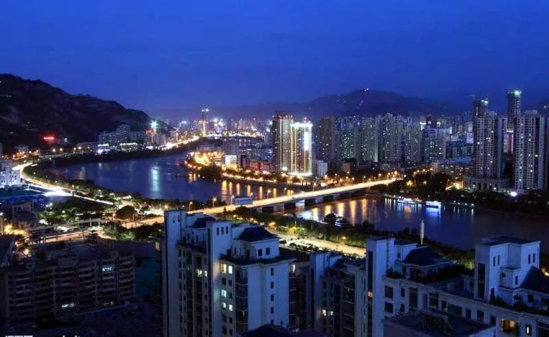 七里河黄河大桥：七里河黄河大桥夜间城市全景；桥位、七跨桥体与两岸建筑可辨认。